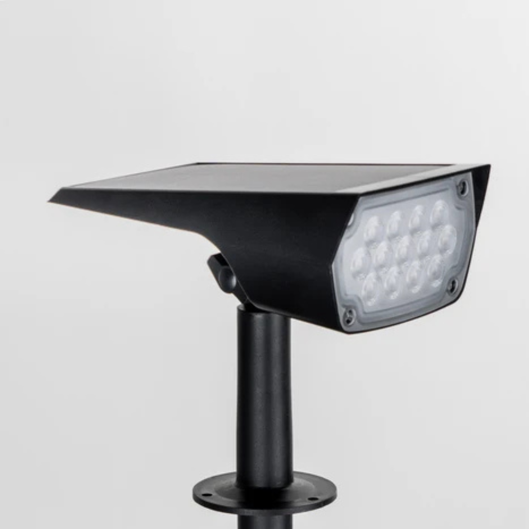 Close-up of the black spotlight head on a plain background, showing the solar panel on top and the LED lens. 4