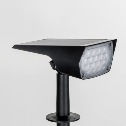 Close-up of the black spotlight head on a plain background, showing the solar panel on top and the LED lens. 4