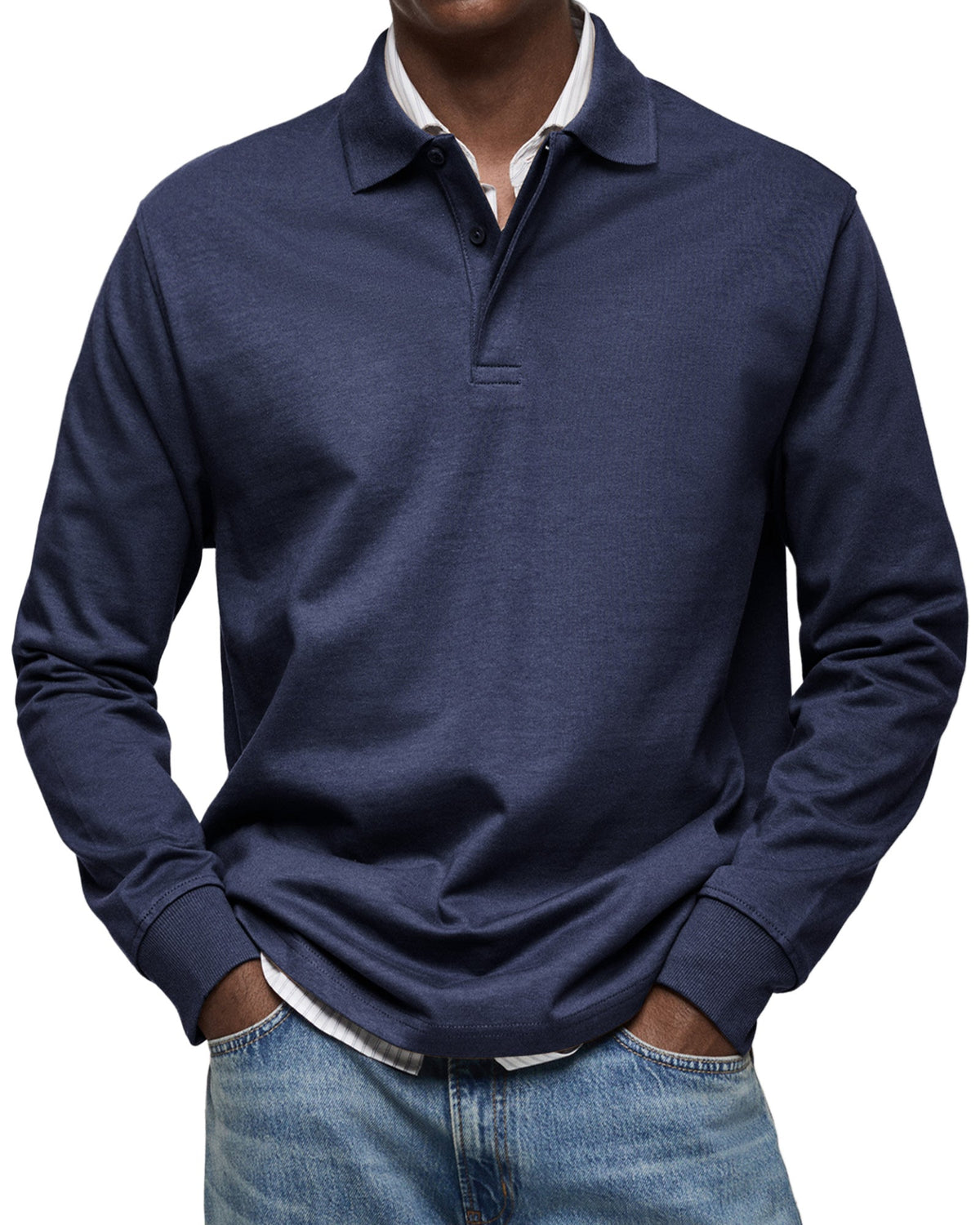 Front view of the polo in dark navy on a model, buttoned placket and ribbed cuffs, worn over a striped shirt. 3