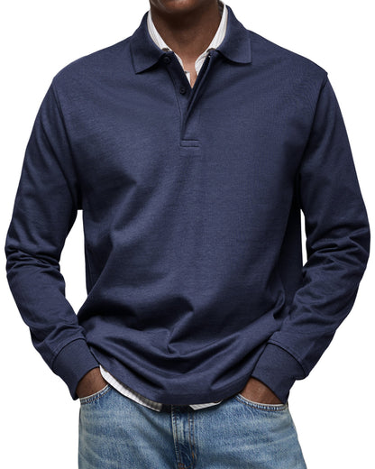 Front view of the polo in dark navy on a model, buttoned placket and ribbed cuffs, worn over a striped shirt. 3