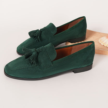 Pair of green tasselled loafers on a plain background, showing tan lining and low black sole 8
