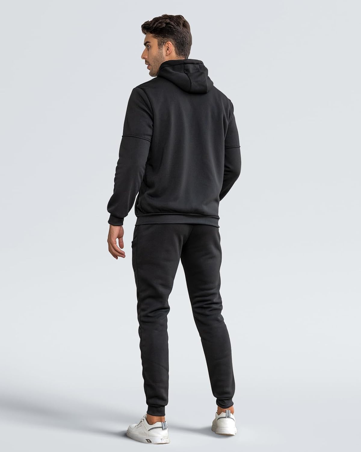 Back view of the black hooded tracksuit worn by a model, showing the plain hood and ribbed cuffs 22