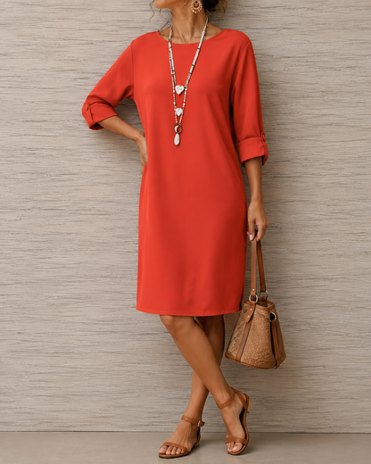 Model in bright orange-red dress with button tab sleeves, hand on hip, holding a woven bucket bag 4