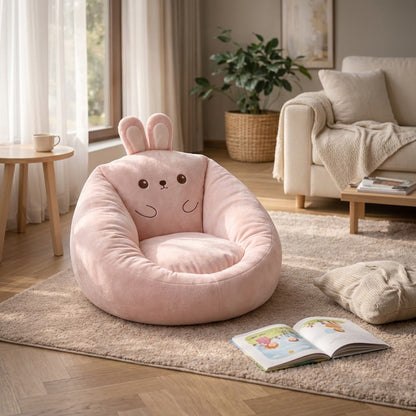 Pink bunny-design bean bag chair with upright ears and embroidered face on a rug beside an open book 7
