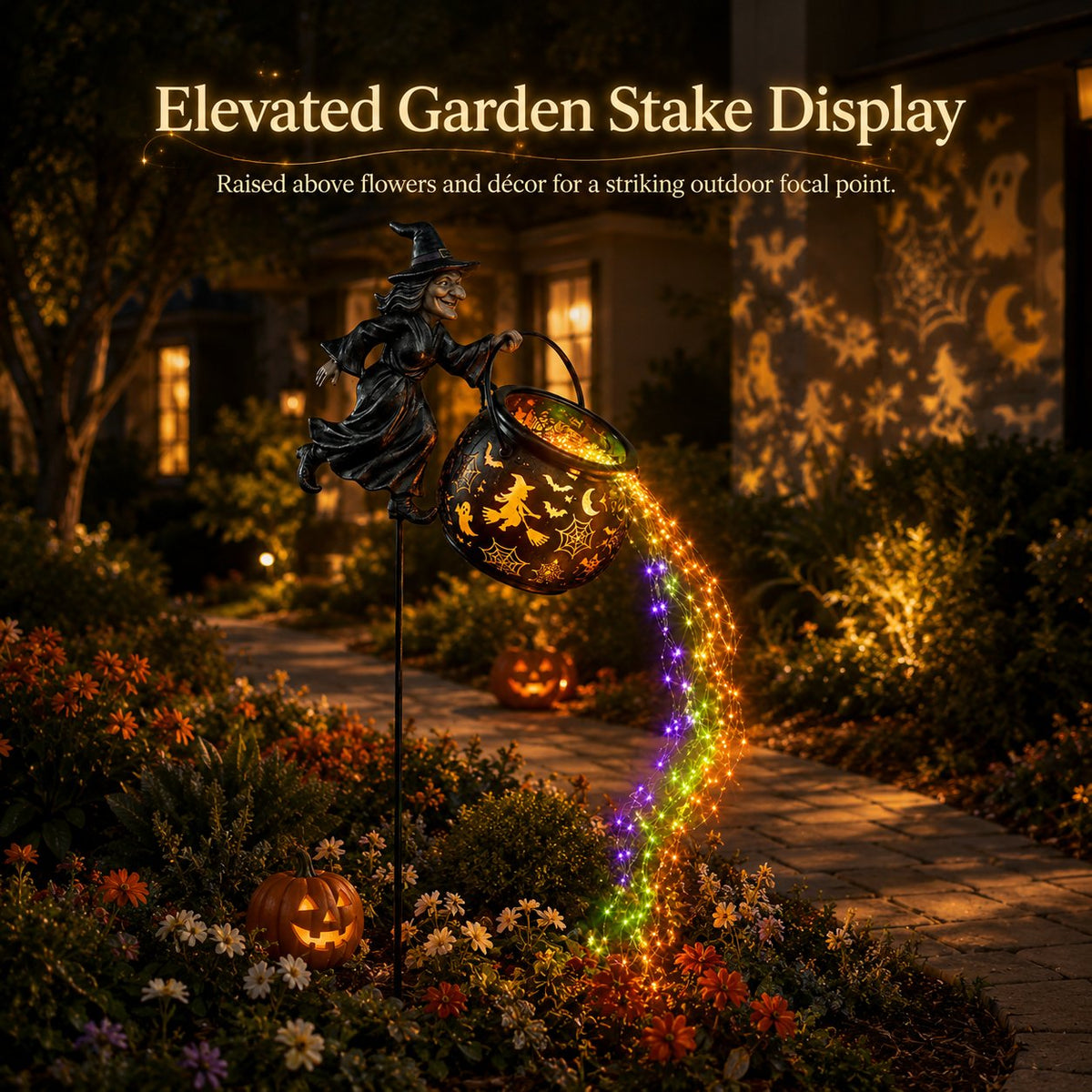 Witch stake raised above flower beds beside a stone path at night, with coloured lights streaming down and pumpkins nearby. 7