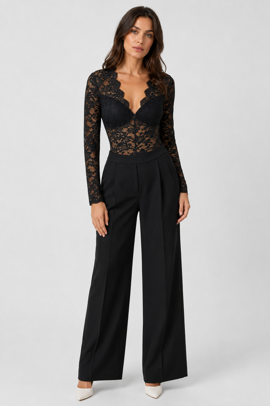 Full-length front view of the black lace bodysuit worn tucked into high-waisted black wide-leg trousers with white pointed heels. 2