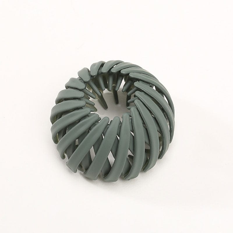 Single matte sage green spiral clip with curved overlapping slats and inner teeth, photographed against a plain background. 9