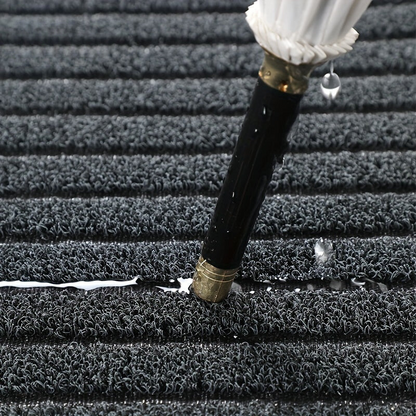 Close-up of a wet umbrella tip pressed into the grey looped pile, with water drops collecting in the grooves. 3