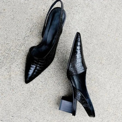 Pair of black croc-textured slingbacks seen from above on a concrete floor, one showing its side 5