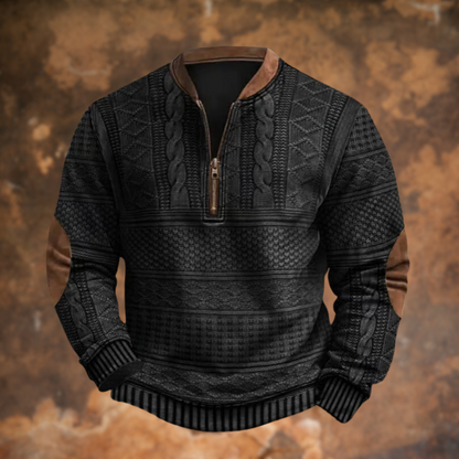 Front view of the black version with cable and diamond knit panels, brown collar trim, zip pull and elbow patches, on a rusty backdrop. 2