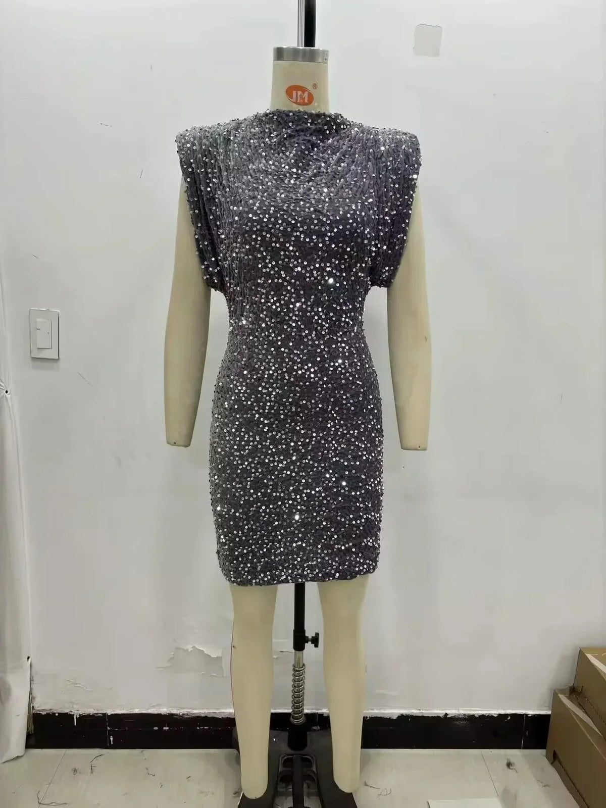 Grey sequinned mini dress with padded shoulders displayed on a mannequin against a plain wall 5