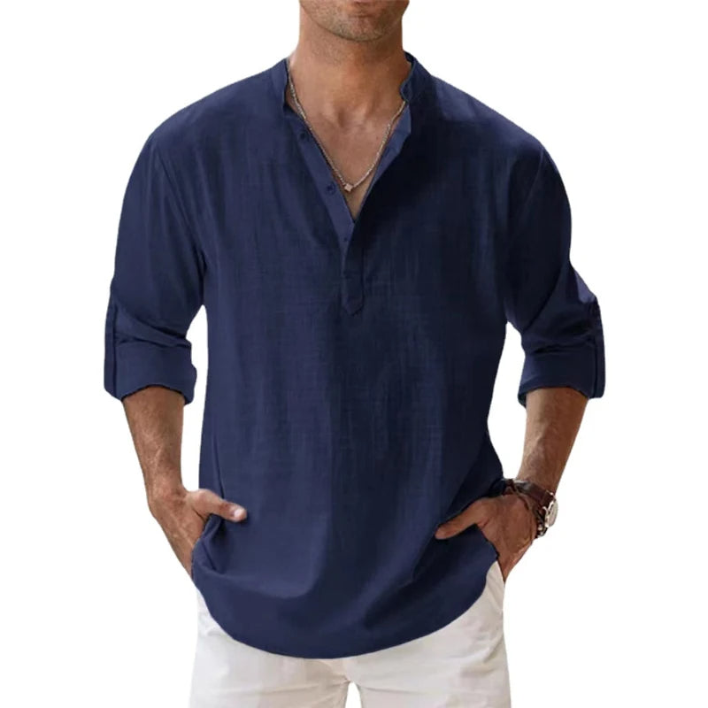 Man wearing the Henley shirt in navy blue, with a short button placket, rolled sleeves and hands in white trousers. 5