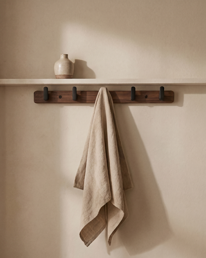 Four-hook rack on a cream wall below a shelf with a small vase, a linen cloth hanging 1