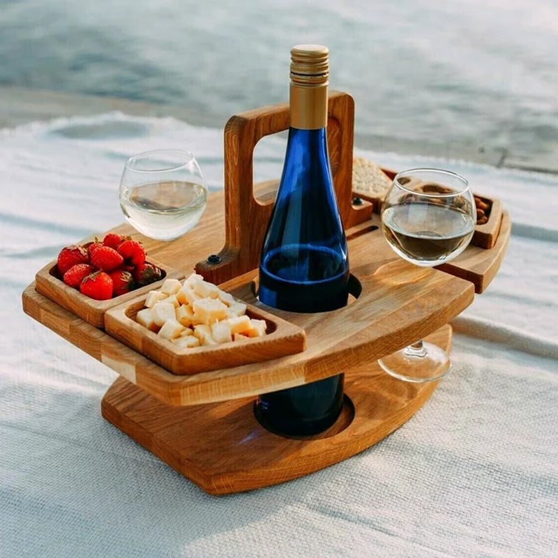 Wooden wine table on a picnic blanket holding a blue bottle, two glasses, strawberries and cheese 1