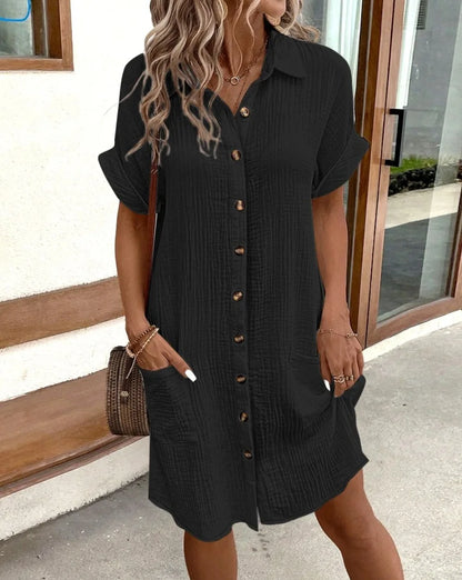 Black crinkle-textured shirt dress with rolled cuffs, styled outdoors with a rattan bag and gold jewellery 5