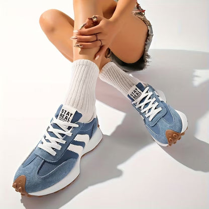 Model sitting with legs crossed, wearing blue suede trainers with white stripes and ribbed white socks 9