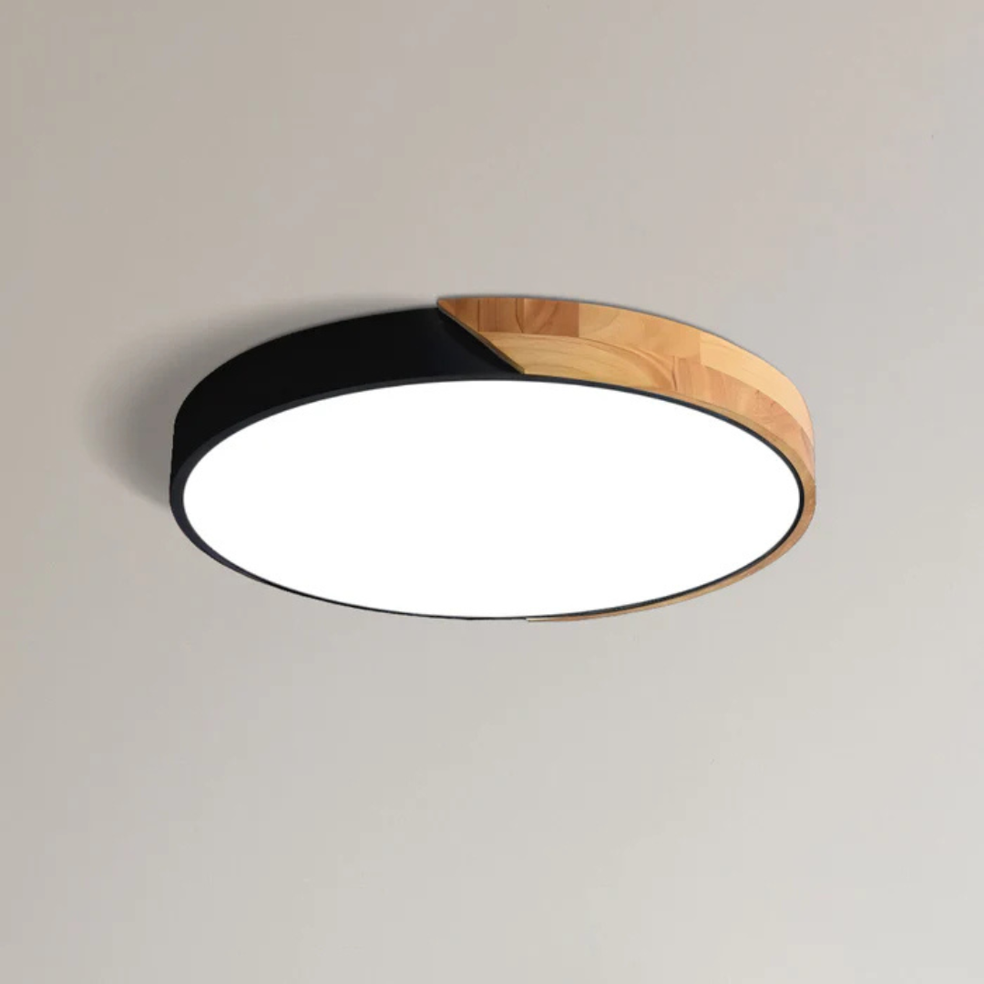 Black and wood round ceiling light shown close up on a plain ceiling, lit 9