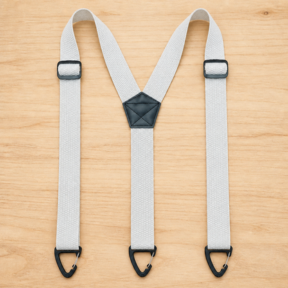 Light grey Y-back suspenders laid flat on wood, with black slide adjusters, triangular clips and a black centre patch. 9
