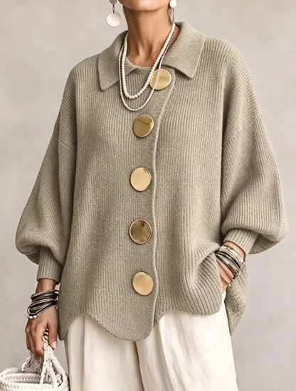 Sage-green taupe ribbed cardigan on a model, with large gold buttons, pointed collar and wavy hem, worn with cream trousers. 17