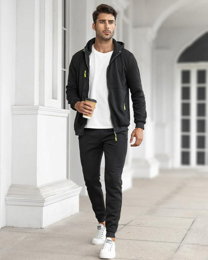 Model walking along a white colonnade in the black tracksuit with the jacket open over a white t-shirt 25