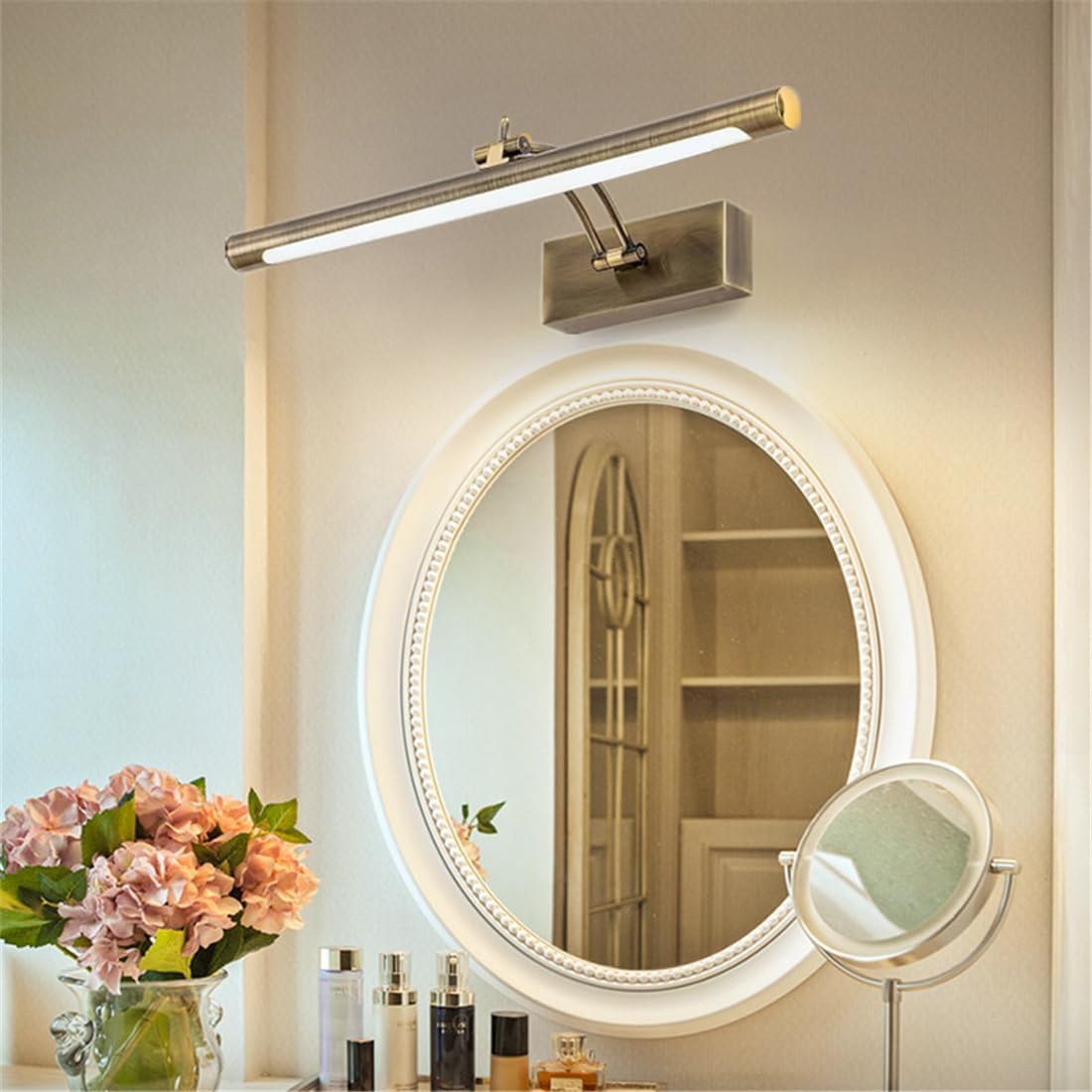 Round-tube brass light above an oval white-framed mirror on a dressing table with flowers 6