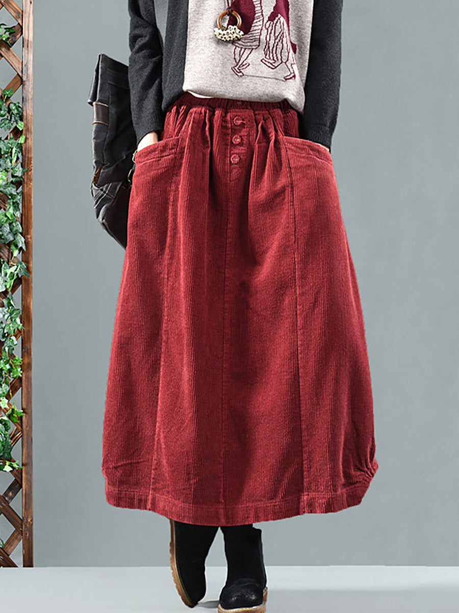Model wears the red corduroy skirt from the front with a grey jumper and black boots 1