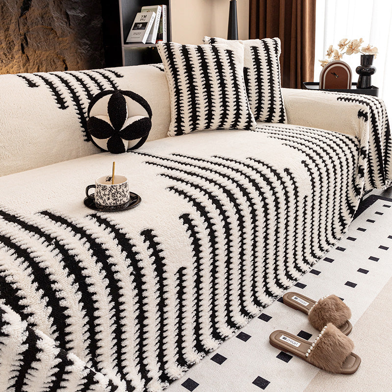 Cream cover with black zigzag stripes on a sofa, with patterned cushions, a teacup and fur slippers 10
