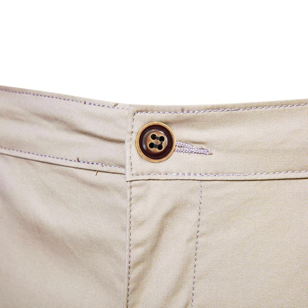Close-up of the waistband fastening, a brown four-hole button with buttonhole and stitching on beige fabric. 5