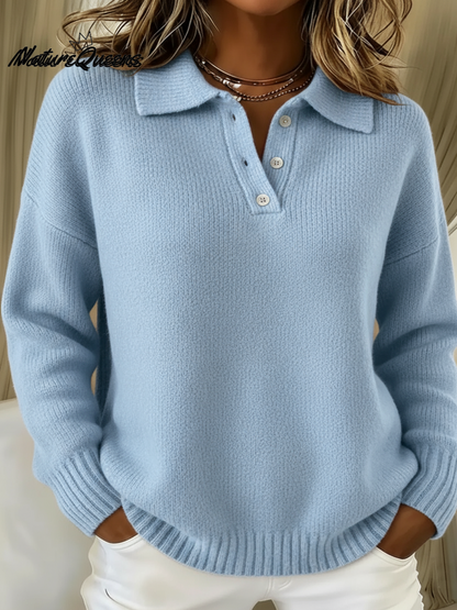 Model wearing the knitted polo jumper in light blue with a button placket, ribbed cuffs and hem, hands in white trouser pockets. 1