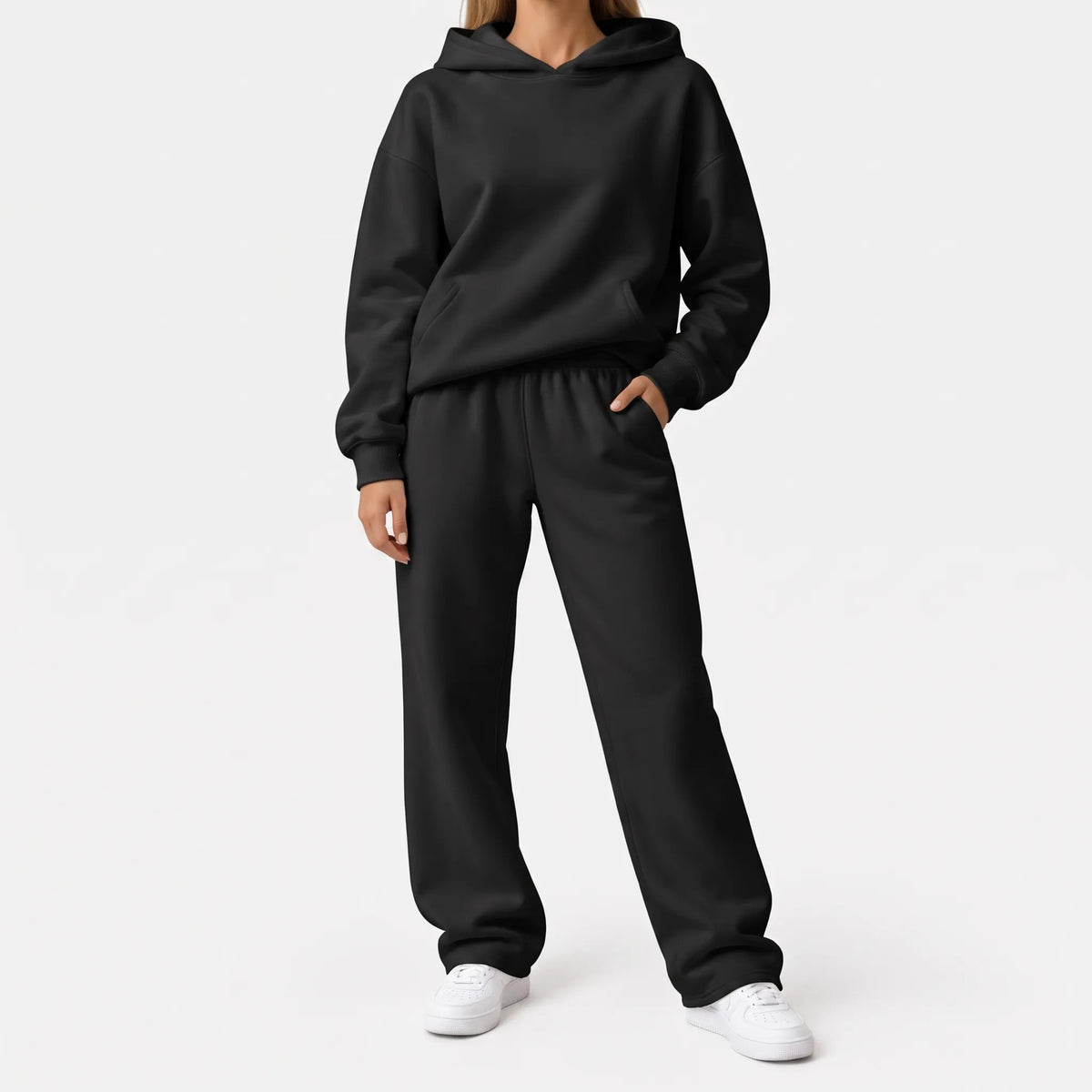 Full-length studio shot of a model in a black hoodie and wide-leg trousers with white trainers 6