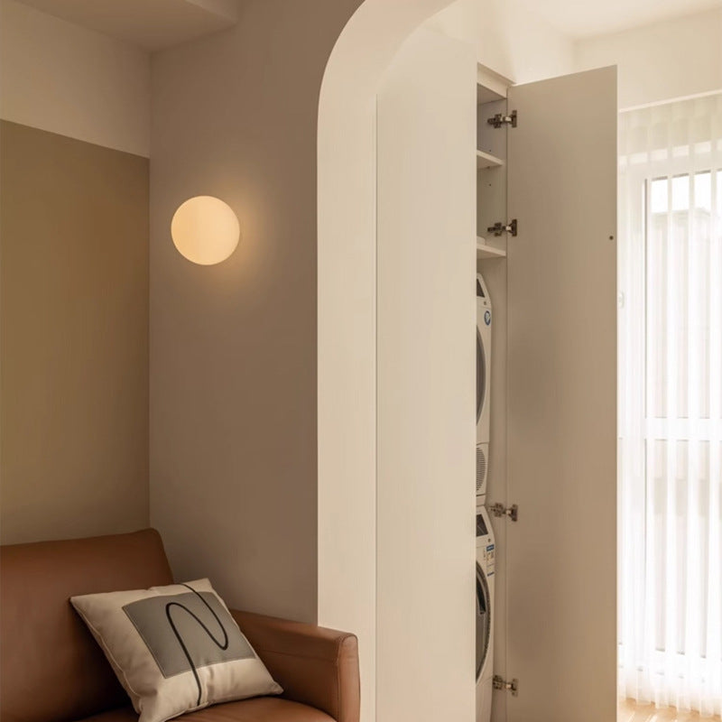 Wall-mounted glowing sphere beside an arched doorway, above a tan leather armchair with a patterned cushion 4