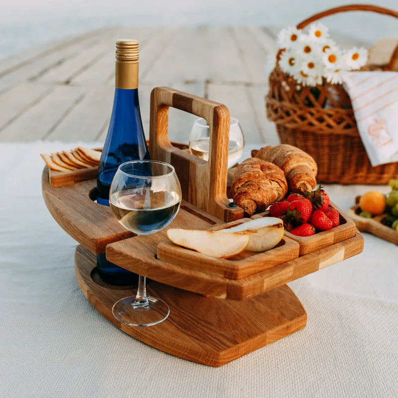 Wooden wine table on a blanket beside a wicker basket, with croissants, pear, strawberries and wine 7