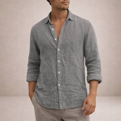 Grey linen shirt worn by a model with one hand in a pocket, cropped at the chin, sleeves rolled. 2