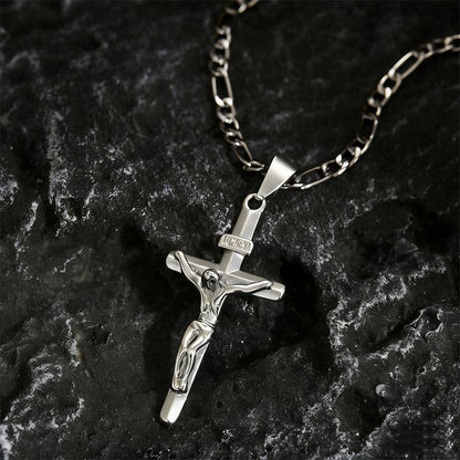 Silver-tone crucifix pendant with INRI plaque and Figaro chain resting on dark textured rock 10
