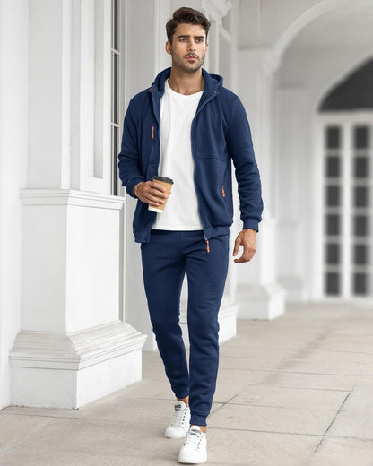 Model walking outdoors in the navy tracksuit with the jacket open over a white t-shirt 6
