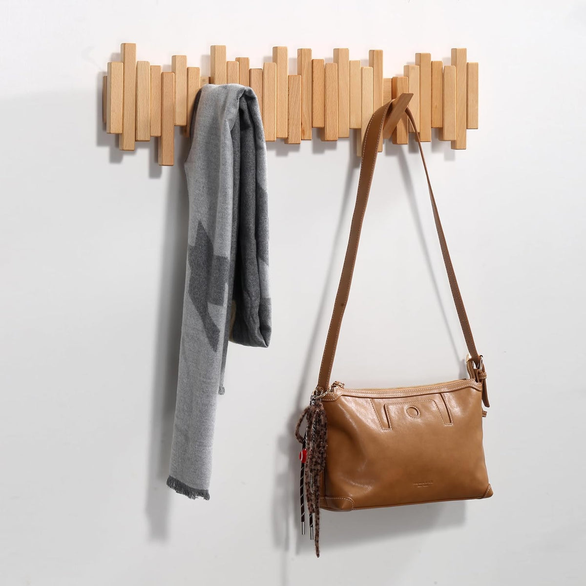 Long light beech-coloured rack on a white wall with a grey scarf and tan shoulder bag 7