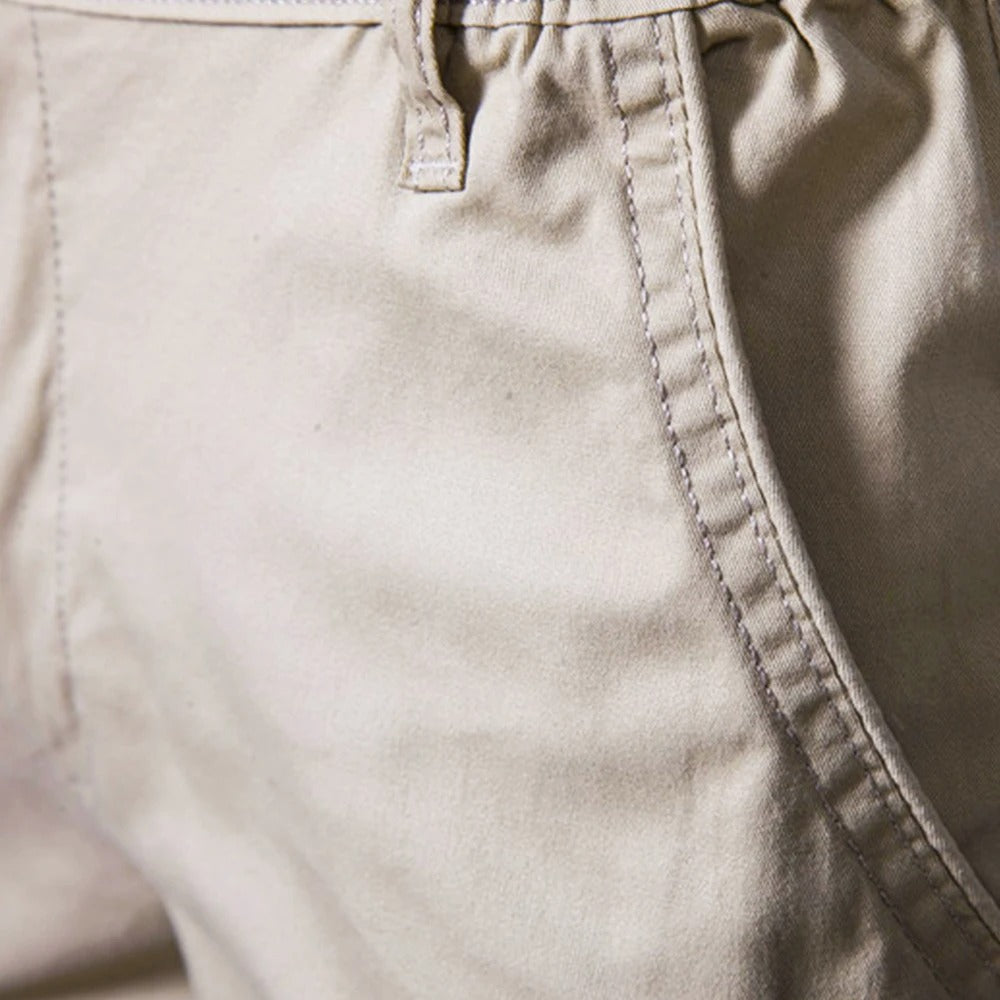 Close-up of the stitched side pocket opening and a belt loop on the beige cotton fabric. 3
