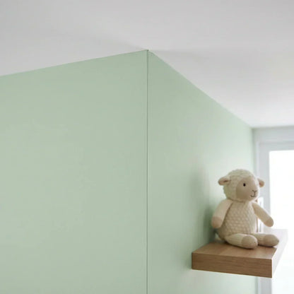 Pale green wall meeting a white ceiling in a crisp straight line, with a soft toy lamb on a shelf 5
