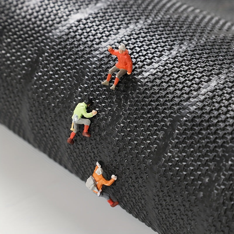 Underside of the mat showing its black woven backing texture, with tiny climbing figures scaling the rolled edge. 7