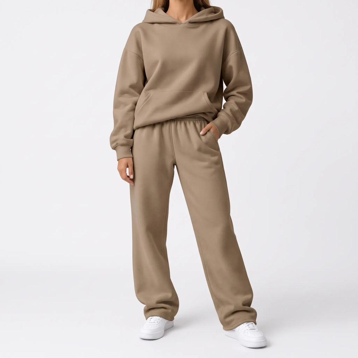 Full-length studio shot of a model in a tan hoodie and wide-leg trousers with white trainers 7
