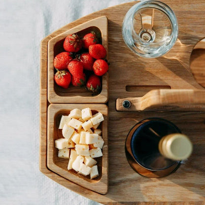 Close-up from above of two wooden snack trays filled with strawberries and cheese cubes, beside the handle and bottle 9