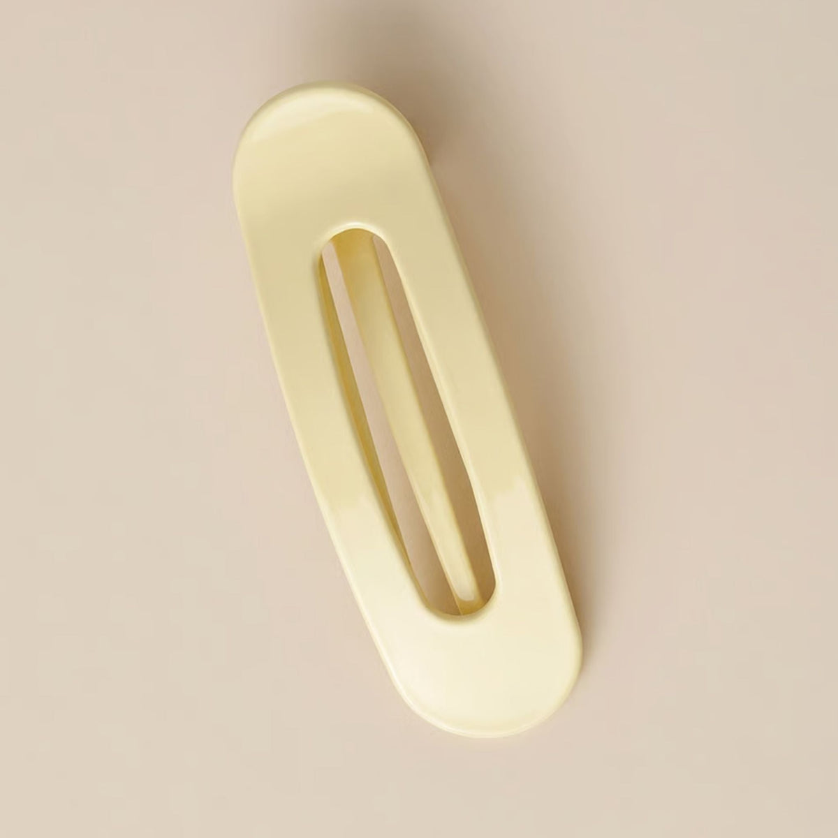 Glossy pale yellow slim flat clip with an open slot, seen from above on a beige background 6