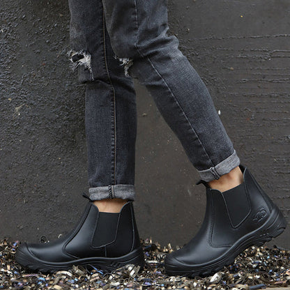 Model in ripped grey jeans wearing black slip-on boots, standing on metal shavings against a dark textured wall 7