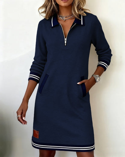 Navy blue half-zip dress with ribbed pocket trims, model standing with her hand in a pocket. 17