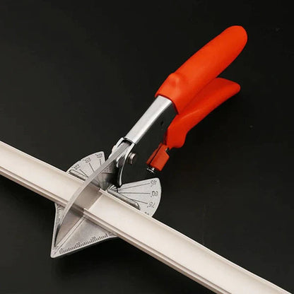Shears with red-orange handles cutting a white plastic strip at an angle on a dark surface 6