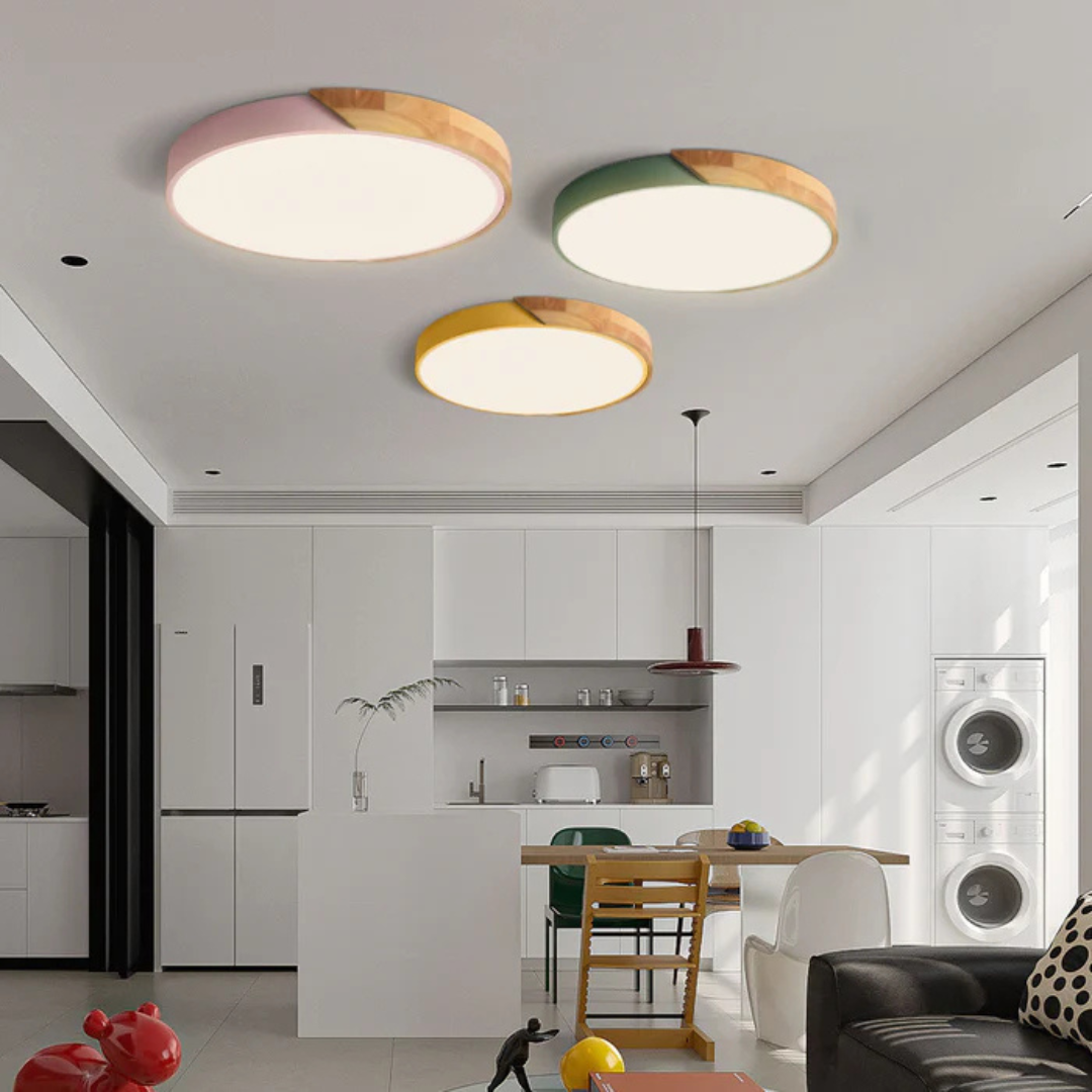 Pink, green and yellow wood-trimmed round ceiling lights hung together above a bright open-plan kitchen and living area 1