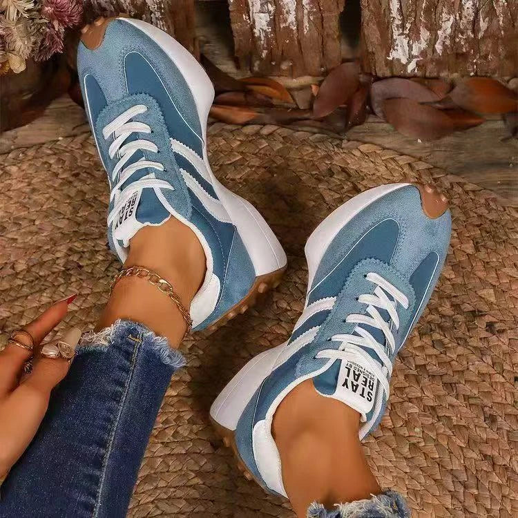 Blue trainers with white stripes seen from above on a model's feet, resting on a woven mat 8