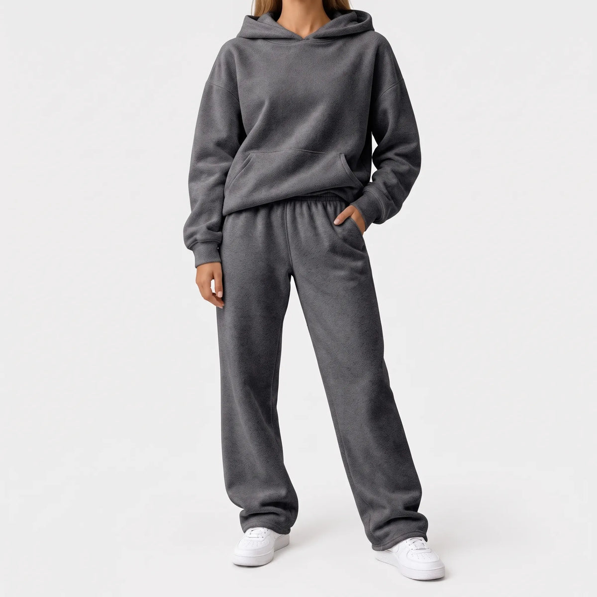 Full-length studio shot of a model in a charcoal grey hoodie and wide-leg trousers with white trainers 8