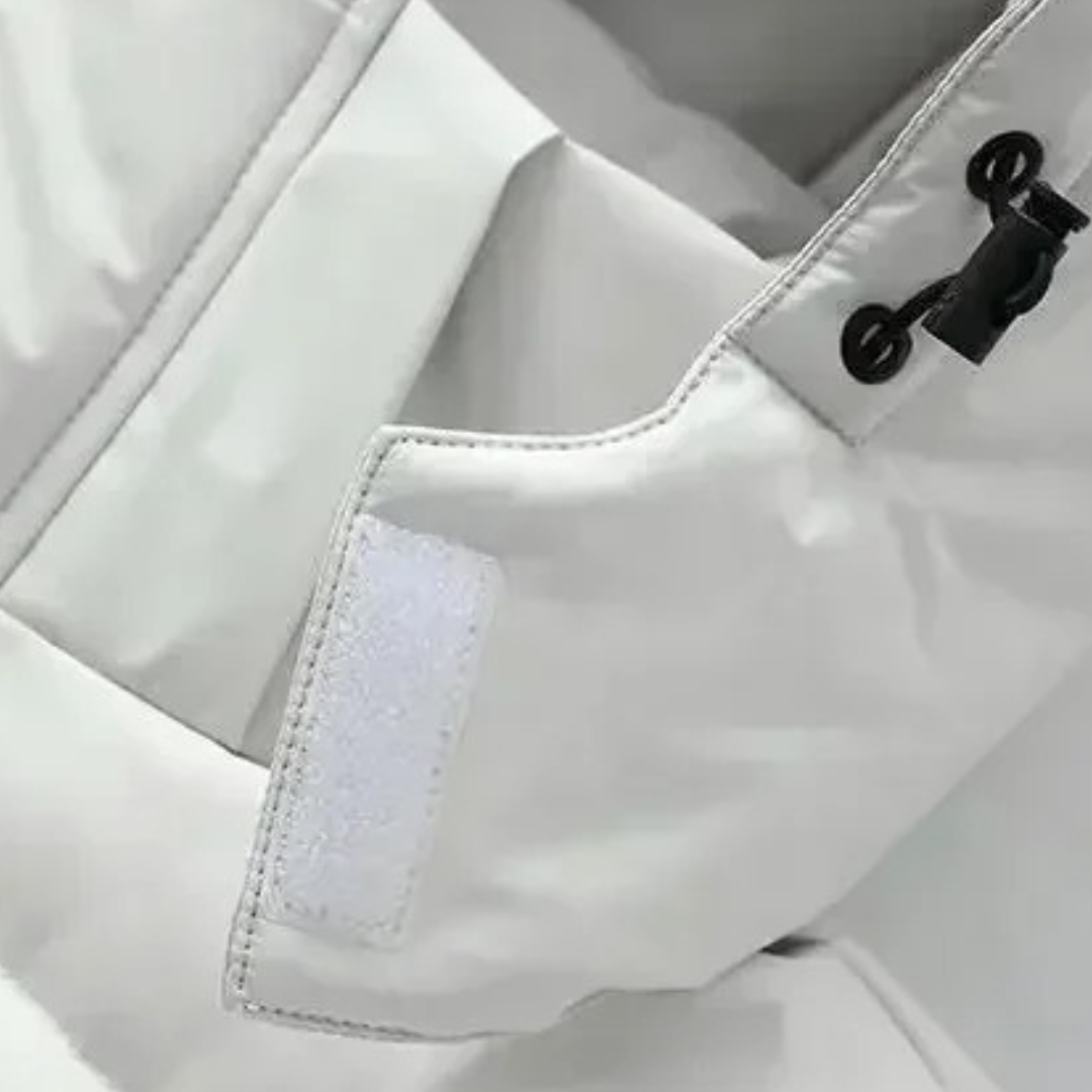 Close-up of a light-coloured coat's hook-and-loop sleeve tab, stitching and hood drawcord toggle 5
