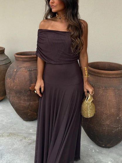 Dark brown one-shoulder dress with draped gathered bodice, shown from the waist up beside clay pots 12